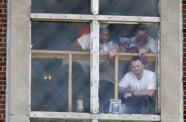 FILE - In this April 28, 2020, file photo, inmates at the Westville Correctional Facility in Westville, Ind., watch protesters from a window. The protesters wanted better safety measures after an outbreak of COVID-19 cases at the prison. For 15 months, The Marshall Project and The Associated Press tracked the spread of COVID-19 through prisons nationwide. Prisons were forced to adapt to unusual and deadly circumstances. But now, as new cases are declining and facilities are loosening restrictions, there’s little evidence to suggest enough substantive changes have been made to handle future waves of infection. (Kale Wilk/The Times via AP, File)