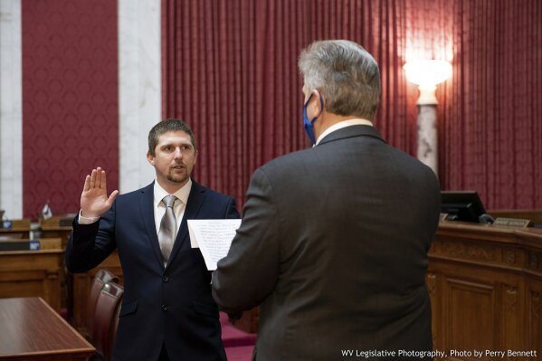 West Virginia House of Delegates member Derrick Evans, left, is given the oath of office Dec. 14, 2020, in the House chamber at the state Capitol in Charleston, W.Va. Evans, a West Virginia state lawmaker resigned Saturday, Jan. 9, 2021 as he faces charges of entering a restricted area of the U.S. Capitol after he livestreamed himself with rioters. (Perry Bennett/West Virginia Legislature via AP)