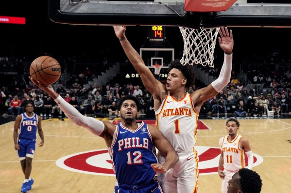 Philadelphia 76ers forward Tobias Harris (12) goes in for a shot as Atlanta Hawks forward Jalen Johnson (1) defends during the first of an NBA basketball game Wednesday, Jan. 10, 2024, in Atlanta. (AP Photo/John Bazemore)