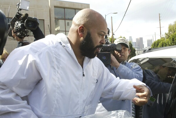 FILE - Rap mogul Marion "Suge' Knight knocks on the window of a waiting taxi, as he leaves the Los Angeles County jail, Wednesday, Feb. 26, 2003, in Los Angeles. Knight was driving the BMW that was transporting rapper Tupac Shakur the night Shakur was shot in 1996. (AP Photo/Damian Dovarganes, File)