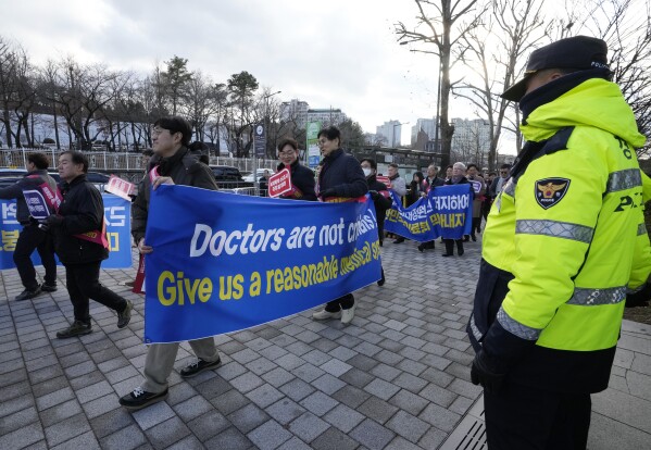 Artsen marcheren naar het presidentiële kantoor tijdens een bijeenkomst tegen het medische beleid van de regering in Seoul, Zuid-Korea, zondag 25 februari 2024.  De Zuid-Koreaanse regering waarschuwde woensdag duizenden stakende artsen om onmiddellijk weer aan het werk te gaan, anders zullen er juridische stappen worden ondernomen.  Collectieve stakingen annuleerden operaties en verstoorden andere ziekenhuisoperaties.  (AP Foto/Ahn Young-joon)