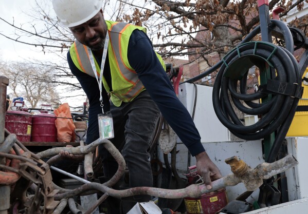 Blackhawk Sewer & Water contractor Khaild Waarith holds a lead pipe that was extracted in Chicago on April 10, 2023. Lead pipes that carry drinking water are a major source of exposure to the metal and the damage is usually permanent. (Antonio Perez/Chicago Tribune via AP)