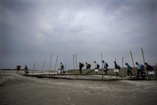 Polling officials walk on the sand to cross the dried river Brahmaputra on the eve of parliament election at Baghmora Chapori (small island) of Majuli, India, April 18, 2024. (AP Photo/Anupam Nath)