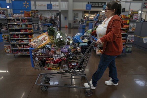 Jodi Ferdinandsen, a client of Jesse Johnson of the Family Resource Center, pushes her grocery cart through Walmart in Findlay, Ohio, Thursday, Oct. 12, 2023. (AP Photo/Carolyn Kaster)
