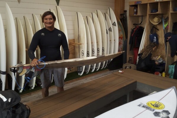 This May 19, 2019 photo provided by Dr. John Jones shows Mikala Jones at Surf Ranch in Lemoore, Calif., holding a surfboard his brother Daniel Jones made using material from the agave plant. Mikala Jones, a Hawaii surfer known for shooting awe-inspiring photos and videos from the inside of barreling waves, has died at the age of 44 after a surfing accident in Indonesia. (Dr. John Jones via AP)