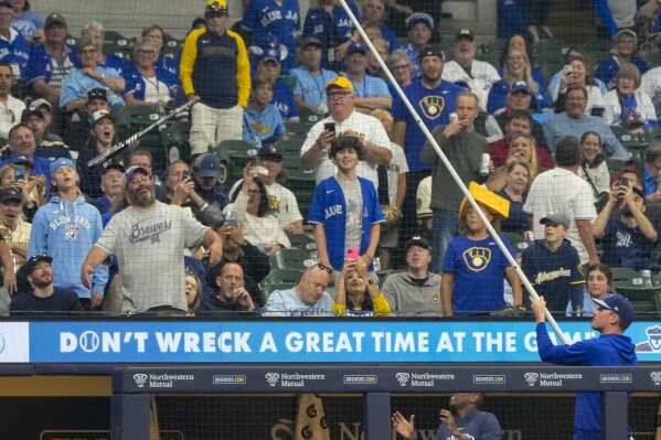 Someone on the Toronto Blue Jays bench tries to get Vladimir Guerrero Jr.'s bat down from a net during the sixth inning of a baseball game against the Milwaukee Brewers Monday, June 10, 2024, in Milwaukee. (ĢӰԺ Photo/Morry Gash)