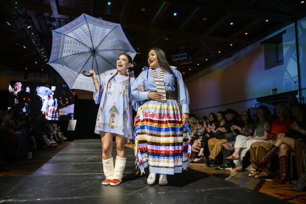 Native Designer Lauren Good Day, right, is accompanied by a model wearing her design after her runway show at the 2025 Native Fashion Show, Friday, May 9, 2025, in Santa Fe, N.M. (AP Photo/Roberto E. Rosales)