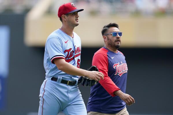 Minnesota Twins starting pitcher Tyler Mahle, left, exits the game with head athletic trainer Michael Salazar during the third inning of a baseball game against the Kansas City Royals Wednesday, Aug. 17, 2022, in Minneapolis. (AP Photo/Abbie Parr)