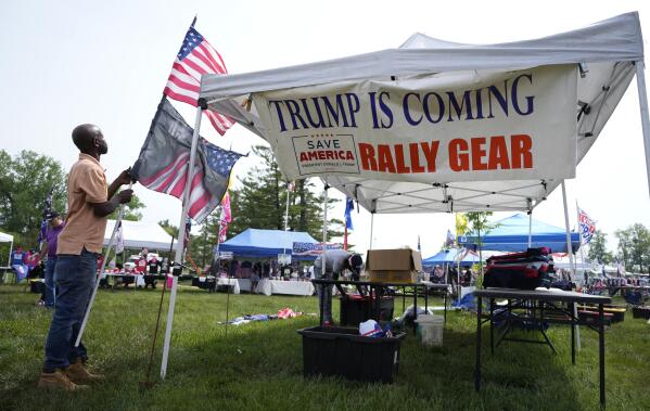 Marvin Hailey, of North Carolina, removes an American flag from a booth after severe weather canceled a campaign rally where former President Donald Trump was expected to speak Saturday, May 13, 2023, in Des Moines, Iowa. (AP Photo/Matthew Putney)