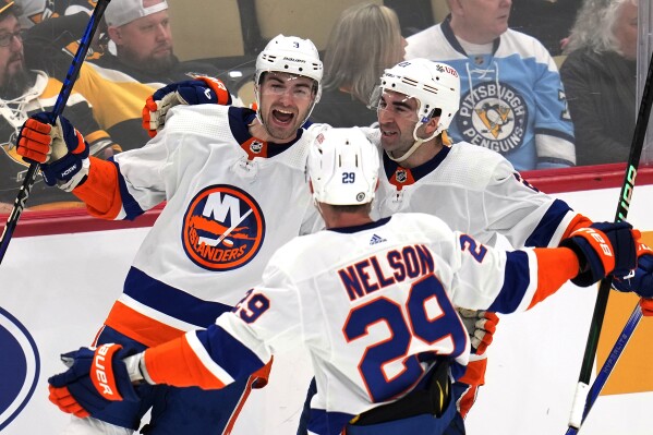 New York Islanders' Adam Pelech (3) celebrates his game-winning goal in overtime with Kyle Palmieri (21) and Brock Nelson during an NHL hockey game in Pittsburgh, Tuesday, Feb. 20, 2024. The Islanders won 5-4. (AP Photo/Gene J. Puskar)