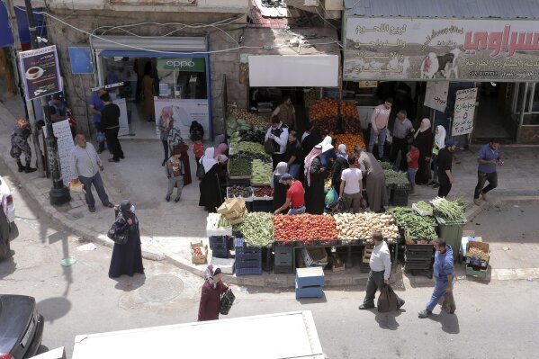People shop for vegetables at the main market in Karak, Jordan, after a curfew was lifted for some southern cities, amid concerns about the coronavirus Wednesday, April 22, 2020. Jordan on Wednesday eased movement restrictions in three large and sparsely populated southern districts where no coronavirus cases have been reported. Life began returning to normal in the districts of Karak, Maan and Tefileh. (AP Photo /Raad Adayleh)