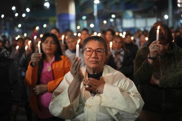 Faithful hold candles during a Mass honoring the late Pope Francis under a highway bridge in the Carlos Mugica neighborhood of Buenos Aires, Argentina, Monday, April 21, 2025. (AP Photo/Rodrigo Abd)