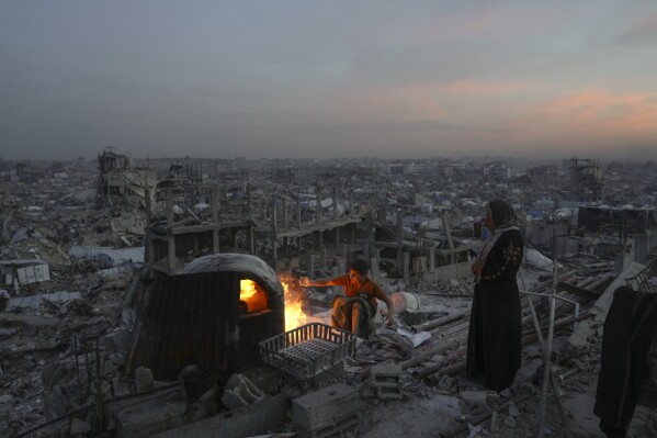 Người Palestine Ali Marouf và mẹ anh Aisha nấu ăn trên ngọn lửa trên mái ngôi nhà bị phá hủy bởi cuộc tấn công trên không và trên bộ của quân đội Israel tại Jabaliya, Dải Gaza, vào thứ Hai, ngày 17 tháng 3 năm 2025. (Ảnh AP/Jehad Alshrafi)