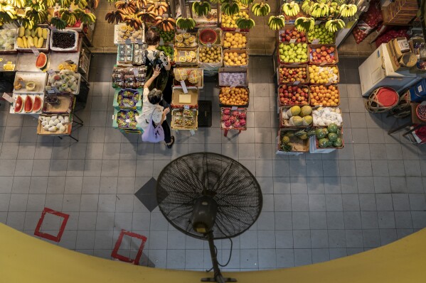 Fruit hangs at a produce stand as patrons shop in a food market in Singapore, Saturday, July 22, 2023. (AP Photo/David Goldman)