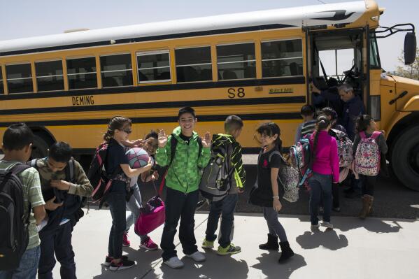 FILE - In this March 31, 2017, file photo, students board a school bus after class at Columbus Elementary School in Columbus, N.M.  New Mexico Public Education Department officials say, Monday, Sept. 28, 2021,  few grade-school students participated in state testing last year and that it is impossible to measure learning loss from the pandemic.  (AP Photo/Rodrigo Abd, File)