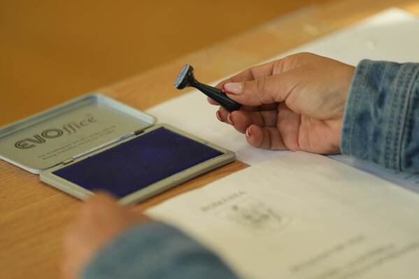 An election official holds a voting stamp during the first round of the presidential election redo in Bucharest, Romania, Sunday, May 4, 2025. (AP Photo/Vadim Ghirda)