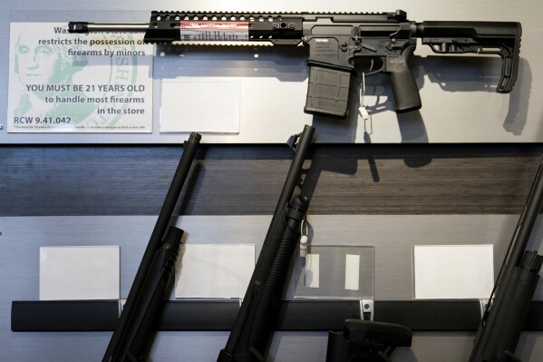 A semi-automatic rifle is displayed above shotguns at Rainier Arms, April 14, 2023, in Auburn, Wash. (AP Photo/Lindsey Wasson, File)