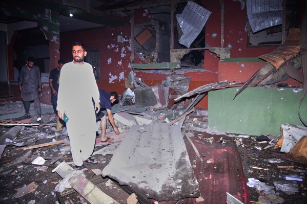 Local residents examine a building damaged from a suspected Indian missile attack near Muzaffarabad, the capital of Pakistan controlled Kashmir, in Wednesday, May 7, 2025. (AP Photo/M.D. Mughal)