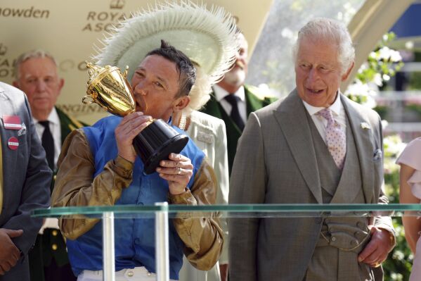 Jockey Frankie Dettori celebrates with the Gold Cup after riding Courage Mon Ami to victory, as Britain's King Charles III and Queen Camilla and look on, on day three of Royal Ascot at Ascot Racecourse, in Berkshire, England, Thursday June 22, 2023. (John Walton/PA via AP)