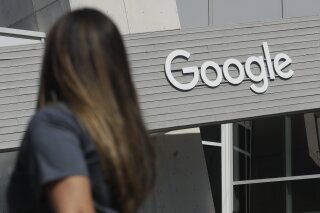 FILE - In this Sept. 24, 2019, file photo a woman walks below a Google sign on the company's campus in Mountain View, Calif. A group of Google engineers announced Monday, Jan. 4, 2021, they have formed a union, creating a rare foothold for the labor movement in the tech industry. (AP Photo/Jeff Chiu, File)