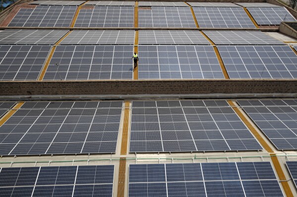 Mark Munyua, CP solar's technician, examines solar panels on the roof of a company in Nairobi, Kenya, Friday, Sept. 1, 2023. Access to electricity remains a major challenge for over half a billion people in sub-Saharan Africa, and power outages are common. In South Africa and Kenya, solar is being used to power major businesses. (AP Photo/Brian Inganga)