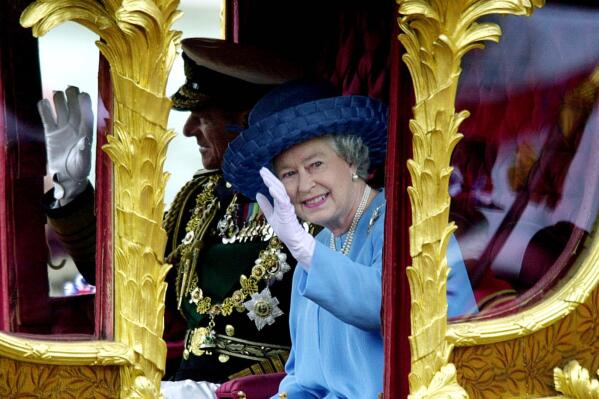 FILE - Britain's Queen Elizabeth II accompanied by her husband the Duke of Edinburgh wave to wellwishers as they ride Tuesday, June 4, 2002, in the State Gold Coach from Buckingham Palace to St Paul's Cathedral, in London for a service of thanksgiving to celebrate her Golden Jubilee. Queen Elizabeth II, Britain’s longest-reigning monarch and a rock of stability across much of a turbulent century, has died. She was 96. Buckingham Palace made the announcement in a statement on Thursday Sept. 8, 2022. (AP Photo/Rebecca Naden/Pool, File)