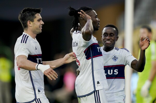 Vancouver Whitecaps defender Sam Adekugbe, center, celebrates his goal against Los Angeles FC with midfielder Richie Laryea, right, and forward Brian White during the first half of an MLS playoff soccer match Saturday, Oct. 28, 2023, in Los Angeles. (AP Photo/Ryan Sun)