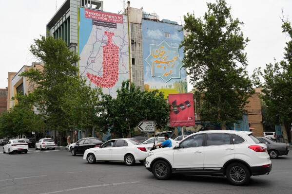 Vehicles drive past an anti-Israel banner showing numerous locations in Israel as a Yemeni dagger (jambiya) with writing in Farsi reading: "All targets are within range, Yemeni missiles for now!", and in Hebrew "All targets are within reach, we will choose", at the Felestin (Palestine) Sq. in downtown Tehran, Iran, Monday, May 5, 2025. (AP Photo/Vahid Salemi)