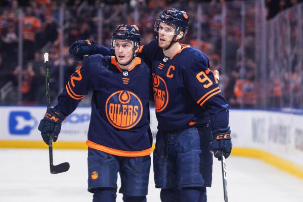 Edmonton Oilers' Tyson Barrie (22) and Connor McDavid (97) celebrate a goal against the Tampa Bay Lightning during the second period of an NHL hockey game Saturday, March 12, 2022, in Edmonton, Alberta. (Jason Franson/The Canadian Press via AP)
