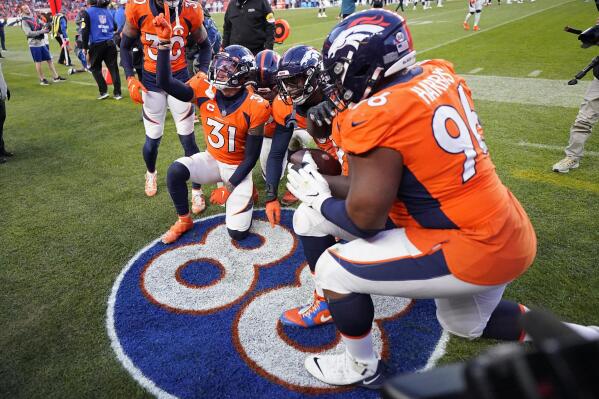 Denver Broncos players kneel on a painted tribute to former Denver Broncos wide receiver Demaryius Thomas during the second half of an NFL football game against the Detroit Lions, Sunday, Dec. 12, 2021, in Denver. (AP Photo/Jack Dempsey)