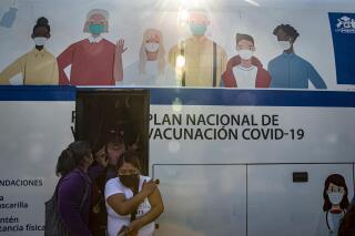 Mujeres salen de un autobús que se usa para inyectar la vacuna contra COVID-19 en Santiago, Chile, el miércoles 26 de mayo de 2021. (AP Foto/Esteban Felix)