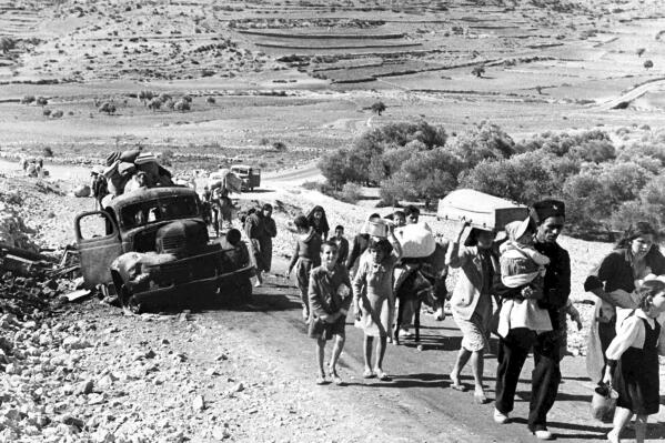 FILE - A group of Arab refugees walks along a road from Jerusalem to Lebanon, carrying their belongings with them on Nov. 9, 1948. The group was driven from their homes by attacks in Galilee. For the first time, the United Nations will officially commemorate the flight of hundreds of thousands of Palestinians from what is now Israel on the 75th anniversary of their exodus, an action stemming from the U.N.’s partition of British-ruled Palestine into separate Jewish and Arab states. (AP Photo/Jim Pringle, File)