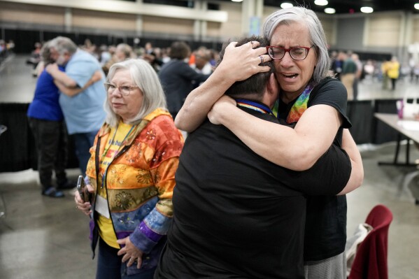 Angie Cox, left, and Joelle Henneman hug after an approval vote at the United Methodist Church General Conference Wednesday, May 1, 2024, in Charlotte, N.C. United Methodist delegates repealed their church’s longstanding ban on LGBTQ clergy with no debate on Wednesday, removing a rule forbidding “self-avowed practicing homosexuals” from being ordained or appointed as ministers.(AP Photo/Chris Carlson)