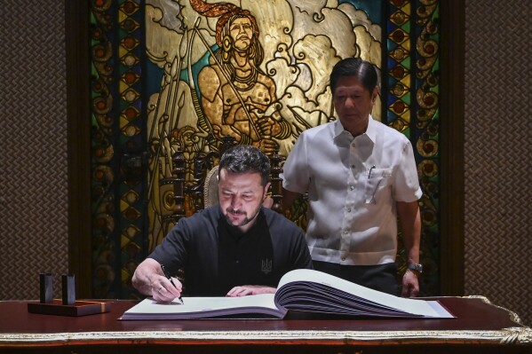 Ukraine's President Volodymyr Zelenskyy, left, signs the guest book beside Philippine President Ferdinand Marcos Jr. at the Malacanang presidential palace in Manila, Philippines on Monday June 3, 2024.(Jam Sta Rosa/Pool Photo via AP)