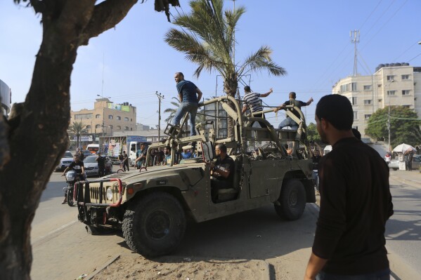 Người Palestine đi trên một chiếc xe quân sự của Israel bị phiến quân Hamas chiếm giữ gần hàng rào Dải Gaza, ở Thành phố Gaza, Thứ Bảy, ngày 7 tháng 10 năm 2023. (Ảnh AP / Abed Abu Reash)