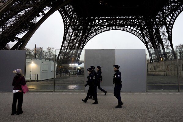 FILE - French policemen patrol near the Eiffel Tower, in Paris, Thursday, Dec. 7, 2023. The giant opening ceremony extravaganza that Paris is planning to hold on the River Seine to launch next year's Olympic Games could be moved if France is hit again in the run-up by extremist attacks, French President Emmanuel Macron said Wednesday Dec.21, 2023. The security, with tens of thousands of police and soldiers deployed, will be intense. (AP Photo/Thibault Camus, File)