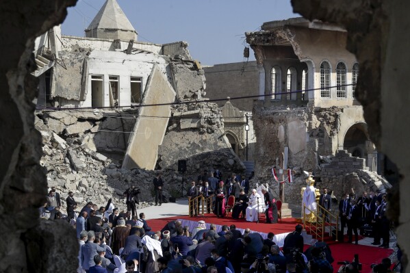 Pope Francis, surrounded by shells of destroyed churches, leads a prayer for the victims of war at Hosh al-Bieaa Church Square, in Mosul, Iraq, once the de-facto capital of IS, March 7, 2021. The long 2014-2017 war to drive IS out left ransacked homes and charred or pulverized buildings around the north of Iraq, all sites Francis visited on Sunday. (AP Photo/Andrew Medichini)