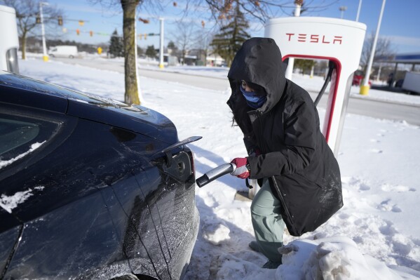 Ankita Bansal prepares to charge her Tesla, Wednesday, Jan. 17, 2024, in Ann Arbor, Mich. A subzero cold snap across the nation has exposed a big vulnerability for electric vehicle owners. It's difficult to charge the batteries in single-digit temperatures. Experts say it's simple chemistry, that the electrons move slowly and don't take in or release as much energy.(AP Photo/Carlos Osorio)