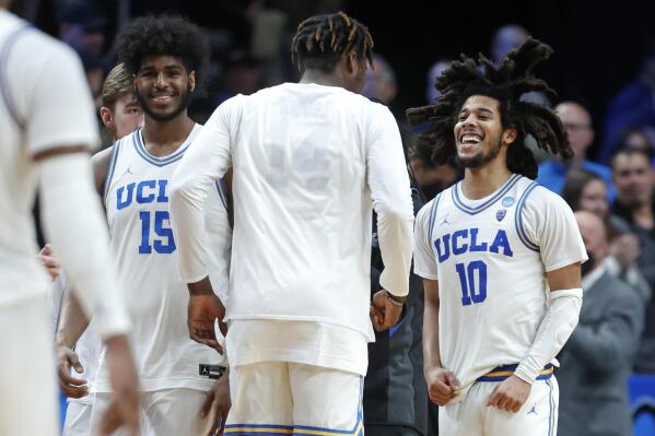 UCLA guard Tyger Campbell (10) reacts with center Myles Johnson (15) and Kenneth Nwuba, center, after a second-round NCAA college basketball tournament game against St. Mary's, Saturday, March 19, 2022, in Portland, Ore. UCLA won 72-56. (AP Photo/Craig Mitchelldyer)