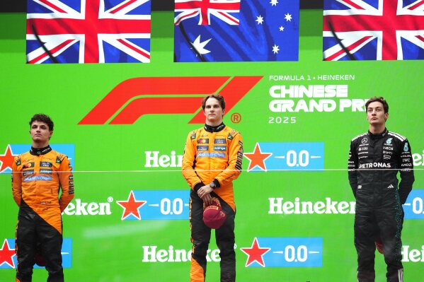 McLaren driver Oscar Piastri of Australia, centre, is flanked on the podium with McLaren driver Lando Norris of Britain, left, and Mercedes driver George Russell of Britain after winning the Chinese Formula One Grand Prix race at the Shanghai International Circuit, Shanghai, Sunday, March 23, 2025. (AP Photo)