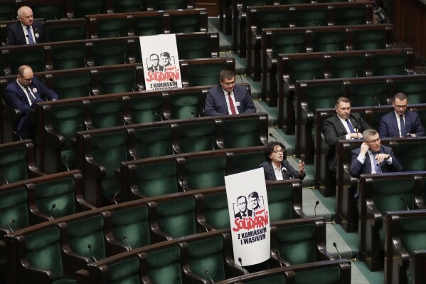Posters with images of imprisoned members of Poland's previous right-wing government, former interior minister, Mariusz Kaminski and former deputy interior minister, Maciej Wasik, who have been convicted of abuse of power, displayed in the opposition section of the lower chamber of Poland's parliament during session, in Warsaw, Poland, Tuesday Jan.16, 2024. The previously governing Law and Justice party, now in the opposition, are protesting the imprisonment and say the two are 