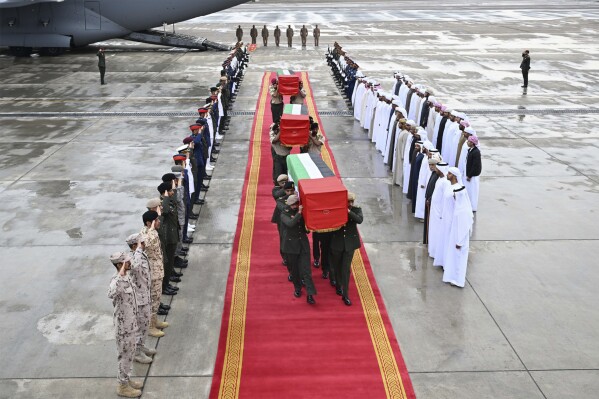 This photo released by Emirates News Agency, WAM, shows the confines of the three flag-draped caskets carry by Emirati armed forces after coming off of an aircraft at Al Bateen Executive Airport in Abu Dhabi, United Arab Emirates, Sunday, Feb. 11, 2024, in Abu Dhabi, United Arab Emirates. The al-Qaida-linked militant group al-Shabab claimed an attack that killed four Emirati troops and a Bahraini military officer on a training mission at a military base in the Somali capital, authorities said Sunday. (WAM via AP)
