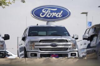 FILE - In this Sunday, Oct. 11, 2020, file photo, a row of 2020 sports-utility vehicles pickup trucks sits at a Ford dealership, in Denver. Ford Motor Co. says it made $3.26 billion in the first quarter, helped by rising vehicle prices and in spite of production cuts due to a global shortage of computer chips. The earnings reversed a nearly $2 billion net loss from a year ago, when Ford burned through cash at the start of the coronavirus pandemic. (AP Photo/David Zalubowski, File)