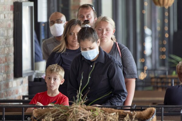 Diners wait for their waitress, center with face mask, to prepare their table at a restaurant in downtown Omaha, Neb., Friday, Aug. 7, 2020. (AP Photo/Nati Harnik)