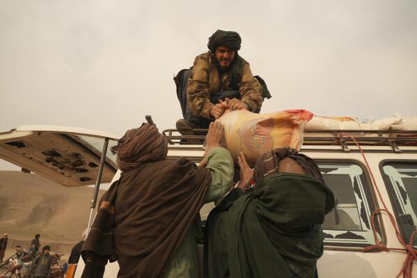Afghan farmers suffering from consequences of the severe drought load food rations on the truck at the distribution point organised by the IFRC, in Sang-e-Atash, Afghanistan, Monday, Dec. 13, 2021. Severe drought has dramatically worsened the already desperate situation in Afghanistan forcing thousands of people to flee their homes and live in extreme poverty. Experts predict climate change is making such events even more severe and frequent. (AP Photo/Mstyslav Chernov)