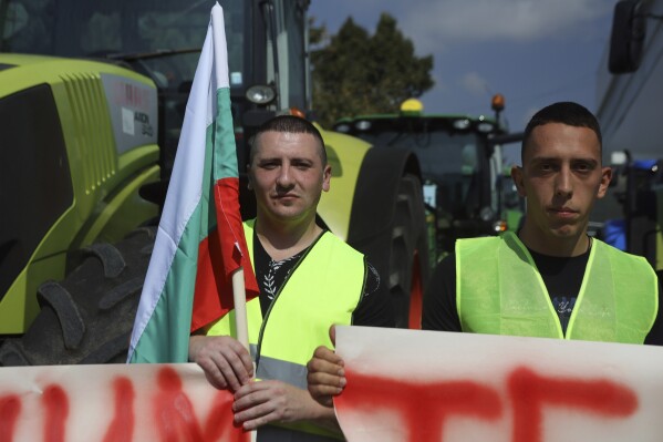 Farmers hold a Bulgarian flag during a protest in the town of Pernik, Monday, Sept. 18, 2023. Farmers in Bulgaria blocked major roads and border crossings nationwide on Monday to protest against their government's decision to lift a ban on imports of food products from Ukraine, complaining that products from the war-torn country will cause an influx and distort local prices. (AP Photo/Valentina Petrova)