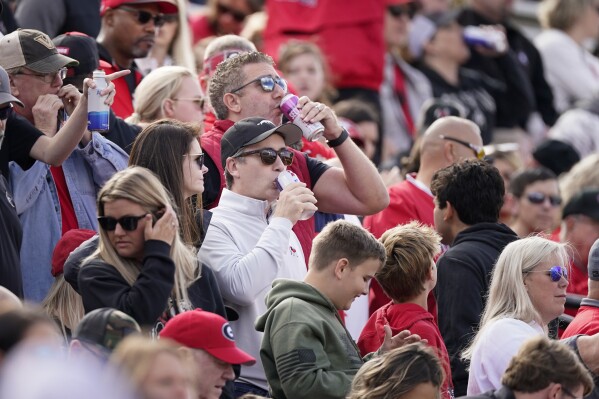 Fans drink alcoholic beverages during an NCAA college football game between Georgia and Vanderbilt, Saturday, Oct. 14, 2023, in Nashville, Tenn. For many years in college football, the booze flowed only outside the stadiums at tailgates. Not anymore. Selling beer and wine has become the norm. According to a survey by The Associated Press of Power Five conference schools and Notre Dame, 55 of 69 of them sell alcohol in the public areas of their stadiums on game days. (AP Photo/George Walker IV)