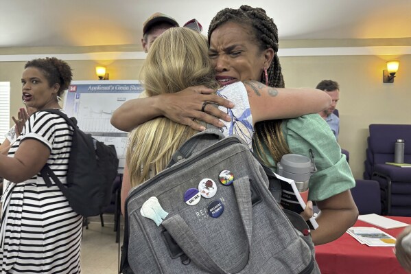 Joy Banner, co-founder of The Descendants Project and a leader in the fight against Greenfield, hugs Kimberly Terrell, then a researcher with the Tulane Environmental Law Clinic, which represented the Descendants Project, moments after hearing that the company would cease plans for a grain elevator facility in the middle of her hometown of Wallace, which is in a heavily industrialized stretch of Louisiana commonly referred to by environmental groups as Cancer Alley. Aug. 6, 2024. (AP Photo/Jack Brook, File)