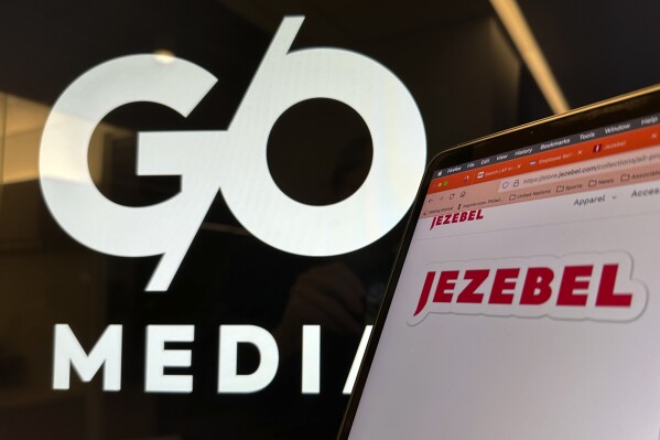 FILE - Logos for G/O Media and Jezebel are displayed on monitors in New York on Friday, Nov. 10, 2023. The irreverent feminist website Jezebel is making a comeback less than a month after it was shut down. Paste Magazine, a digital pop culture publication, announced Wednesday, Nov. 29, 2023, that it was buying Jezebel.com from G/O Media, which closed it and laid off its staff earlier this month. (AP Photo/Peter Morgan, File)