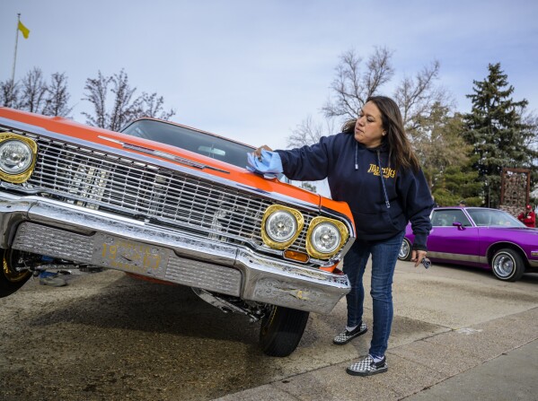 Vicki Garcia cleans her 1963 lowrider Chevy Impala outside of the State Capitol in Santa Fe, N.M., on Lowrider Day, Tuesday, Feb. 11, 2025. (AP Photo/Roberto E. Rosales)